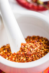 Sticker - Dry chili pepper flakes. Crushed red peppers in mortar on white table.