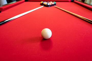 Red billiard table with billiard balls and cues