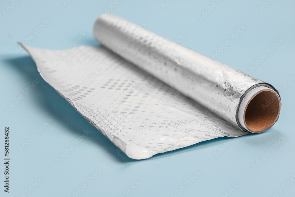 Roll of aluminium foil on color background