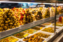 Counter Of A Market With Piles Of Food, Olives And Pickles In A Colorful Exhibition, Mercado San Miguel, Madrid.