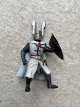 Ids Toy Collectible A White Full-length Figure Knight Templar With Shield Ready To Fight Stands Proudly Against A Grey Stone Background.