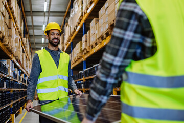 Wall Mural - Smiling warehouse workers carring a solar panel.