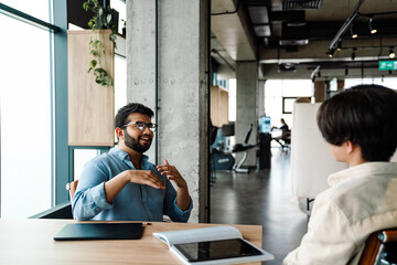 Two male colleagues talking while working together in office