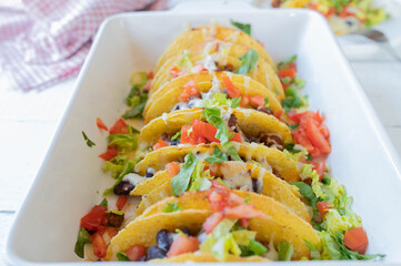 Wall Mural - Tex mex taco casserole with ground beef, kidney beans, tomatoes, lettuce and cheese topping in a casserole dish.