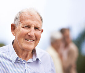 Canvas Print - Getting older...but also happier. Portrait of a senior man standing outside with people blurred in the background.