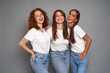 © gpointstudio - Portrait of three young caucasian women wearing blue jeans and white tshirt on grey background