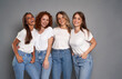 © gpointstudio - Four young caucasian women wearing blue jeans and white tshirt on grey background