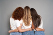 © gpointstudio - Back view of three young caucasian women wearing blue jeans and white tshirt on grey background
