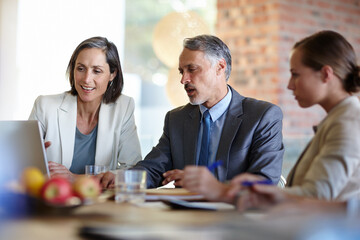 Canvas Print - Demonstrating the new website. A cropped shot of a businessman showing two of his colleagues something on his laptop during a meeting.