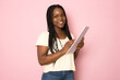 © Danko - Young smiling happy african american girl teen student wear casual clothes hold books isolated on pink color background studio portrait. Education in high school university college concept.