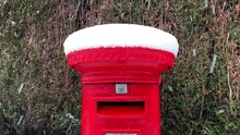 A Red Post Mailbox In Winter At Christmas Covered With Snow. A Traditional English Post Box Snowing.