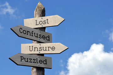 Wall Mural - Lost, confused, unsure, puzzled - wooden signpost with four arrows, sky with clouds