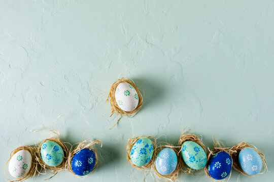 Fototapete - Row of hand painted Easter eggs on light green concrete background. Flat lay, top view with copy space