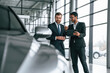 © standret - Looking at the vehicle. Man is consulting the customer in the car showroom
