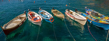 Seven Wooden Boats Are Lined Up In The Sea In Manarola, Cinque Terre, Italy