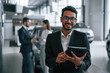 © standret - Man standing in front of his coworkers. Three people are working together in the car showroom