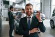 © standret - Handsome man is standing in front of his coworkers. Three people are together in the car showroom
