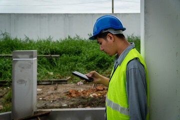  engineer in safety gear wearing hard hat using mobile phone at construction site