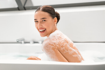 Wall Mural - Female Taking Bath With Foam Smiling Looking At Camera Indoors