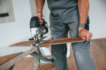 Wall Mural - Cutting the planks. Man is installing new laminated wooden floor