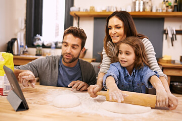 Canvas Print - Lets check the recipe...a happy family following an online recipe while baking in the kitchen.