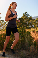 Canvas Print - Enjoying nature on the run. a young woman doing a trail run.