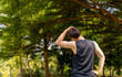 sporty handsome man stretching neck and head after jogging in city public park during summer day, young guy spend quality time on weekend workout outdoor in nature for healthy and active lifestyle