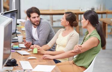 Canvas Print - Working together to make the project a success. a group of young businesspeople talking at their desk.