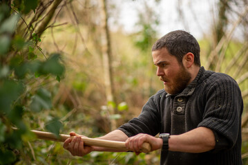 handsome man 30 years old cuts a tree with an ax