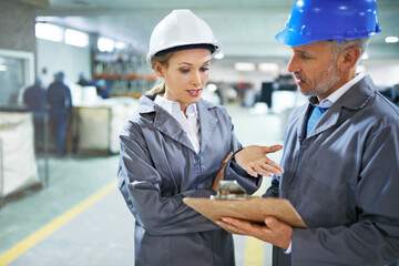 Poster - Streamlining shipping logistics on the factory floor. two managers in workwear talking together over a clipboard while standing on the printing factory floor.