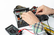 © OLEKSANDR - repair of a disassembled Computer Power Supply Unit, tester measurement, on a white background