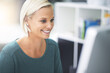 © T Rose/peopleimages.com - Getting her work done with a smile. a businesswoman working on her office computer.