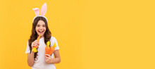 Happy Hungry Teen Girl In Bunny Ears Hold Carrot On Yellow Background, Easter. Easter Child Horizontal Poster. Web Banner Header Of Bunny Kid, Copy Space.