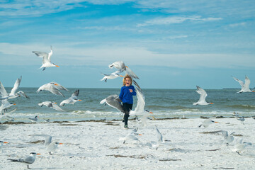 Carefree child. Little kid boy having fun on Miami beach. Happy cute child running near ocean hunting seagull birds on warm summer day.