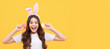 surprised kid in bunny ears hold eggs on yellow background. Easter child horizontal poster. Web banner header of bunny kid, copy space.