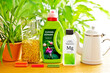 Different indoor fertilizers: fertiliser sticks or spikes, granules, liquid and speciality plant food in bottles with german labels, against a green plants background.