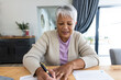 Leinwandbild Motiv Portrait of biracial senior woman analyzing bills on wooden table while sitting at home
