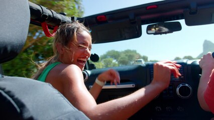 Wall Mural - Group of female friends in open top car laughing on road trip through countryside - shot in slow motion