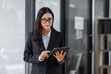 Wall Mural - Portrait of Young business asian woman using tablet, standing in office.
