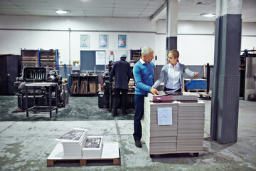 Poster - Discussing improvements to production. two colleagues inspecting inventory in a printing factory.