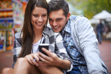 Poster - Enjoying the ease of mobile photography. A happy young woman showing her boyfriend something on her smartphone.