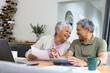 © Wavebreak Media - Cheerful biracial senior couple looking at each other while analyzing bills on table at home