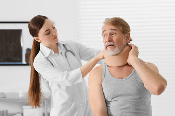 Orthopedist applying cervical collar onto patient's neck in clinic