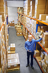 Poster - Managing shipping logistics. a mature man working inside in a distribution warehouse.