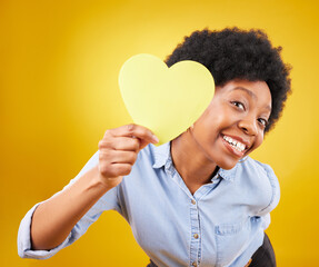 Wall Mural - Portrait, heart and social media with a black woman in studio on a yellow background for love or affection. Emoji, shape and romance with an attractive young female feeling excited for valentines day