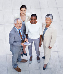 Theyre a force to be reckoned with. HIgh angle portrait of a diverse and confident group of businesspeople standing with a digital tablet.