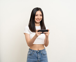 Excited Beautiful young asian women play mobile game and standing on isolated white background. Playing game on smartphone winning victory moment. Very enjoy and fun relax time