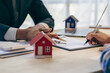 © ArLawKa - Real estate agents offer contracts to buy or rent housing. Businessman touching a small building house model property and real estate insurance close up pictures