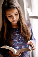 Wall Mural - Today a reader tomorrow a leader. Portrait of a cute little girl reading at home.