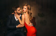 Portrait couple in love man and woman embracing hugging fashion model posing. luxurious male black suit costume. girl in elegant evening red dress, open naked sexy back. Modern stylish guy, dark room